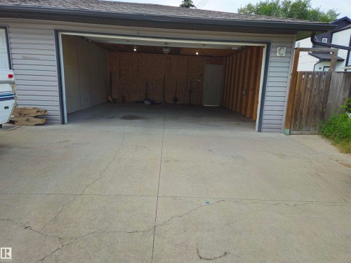 Attached garage with gray horizontal siding, asphalt shingle roof, and exposed wood stud framing - 11625 88 Street Nw, Edmonton, AB 