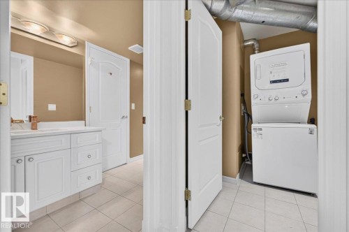 White vanity with under-sink cabinetry and drawers, an integrated sink, and a wall-mounted mirror - #1102 10909 103 Av Nw, Edmonton, AB - Indoor Photo Showing Laundry Room