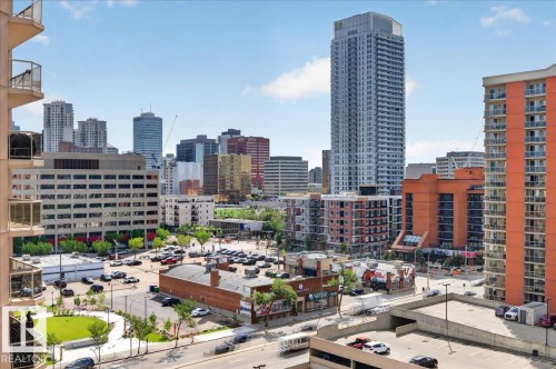 Cityscape featuring multiple high-rise structures, a mix of commercial and residential buildings, and a paved parking area - #1102 10909 103 Av Nw, Edmonton, AB - Outdoor With Balcony With View