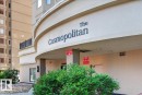 Curved building facade with "The Cosmopolitan" signage, ground-floor entry, exterior light fixtures, and low-maintenance landscaping - #1102 10909 103 Av Nw, Edmonton, AB  - Outdoor 