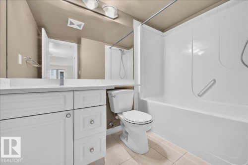White vanity with panel-front cabinetry, a single basin sink, and an extended countertop - #1102 10909 103 Av Nw, Edmonton, AB - Indoor Photo Showing Bathroom