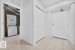 White paneled entry door with brass hardware, stacked laundry appliances, and tile flooring - 