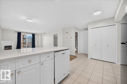 Kitchen island with solid surface countertop, integrated dishwasher, and white cabinetry - #1102 10909 103 Av Nw, Edmonton, AB - Indoor