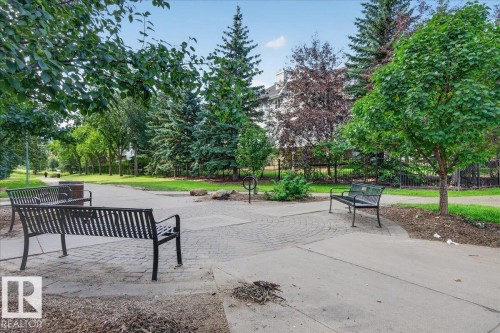 Paved pathways with integrated seating areas, surrounded by mature trees and landscaped green spaces - #1102 10909 103 Av Nw, Edmonton, AB - Outdoor