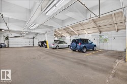 Underground parking garage featuring concrete flooring, exposed ceiling beams, and fluorescent lighting - 