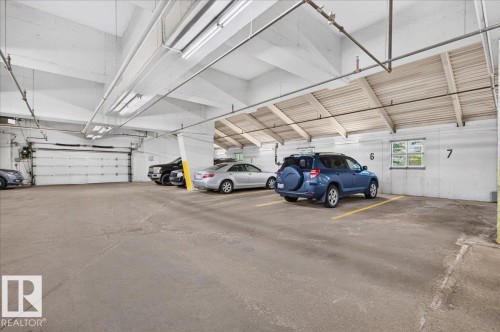 Underground parking garage featuring concrete flooring, exposed ceiling beams, and fluorescent lighting - #1102 10909 103 Av Nw, Edmonton, AB - Indoor Photo Showing Garage