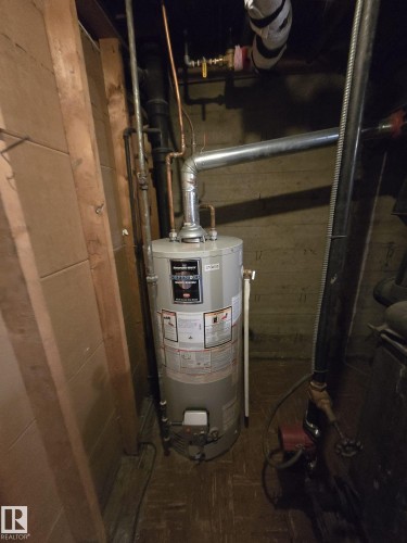 Hot water heater with galvanized steel flue pipe and copper piping - 9839 81 Avenue Nw, Edmonton, AB - Indoor Photo Showing Basement