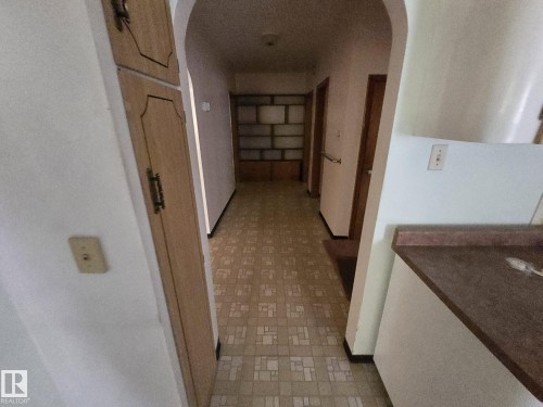 Hallway featuring built-in shelving, archway, and patterned floor tile - 9839 81 Avenue Nw, Edmonton, AB - Indoor