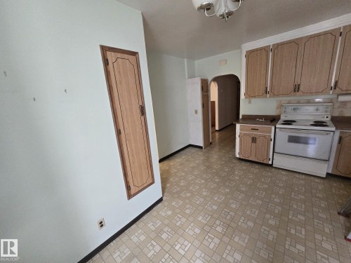 Kitchen featuring patterned flooring, wood-finish cabinetry, and a white oven/range - 9839 81 Avenue Nw, Edmonton, AB - Indoor Photo Showing Kitchen