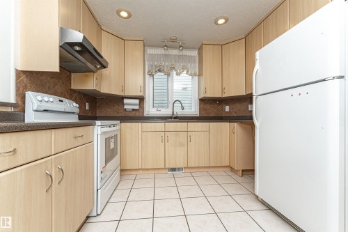 Kitchen featuring light wood-finish cabinetry, dark countertops, a tile backsplash, and recessed lighting - 12241 93 Street Nw, Edmonton, AB - Indoor Photo Showing Kitchen