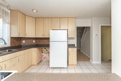 Light wood-finish cabinetry with dark countertops, a tile backsplash, and recessed lighting - 12241 93 Street Nw, Edmonton, AB - Indoor Photo Showing Kitchen