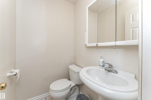 Pedestal sink with chrome-finish faucet, toilet, and mirrored medicine cabinet - 12241 93 Street Nw, Edmonton, AB - Indoor Photo Showing Bathroom