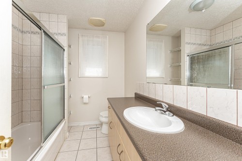 Tub and shower combination with sliding glass enclosure, white tile surround, and tile flooring - 12241 93 Street Nw, Edmonton, AB - Indoor Photo Showing Bathroom