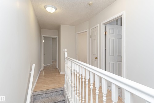 Hallway featuring wood-finish flooring, white paneled doors, and a white baluster railing - 12241 93 Street Nw, Edmonton, AB - Indoor Photo Showing Other Room