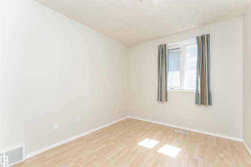 Light wood-finish flooring with white baseboards, a white window frame, and a textured white ceiling - 12241 93 Street Nw, Edmonton, AB - Indoor Photo Showing Other Room