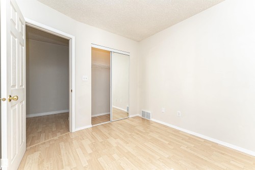 Light wood-finish flooring, mirrored sliding closet doors, and a neutral wall palette - 12241 93 Street Nw, Edmonton, AB - Indoor Photo Showing Other Room