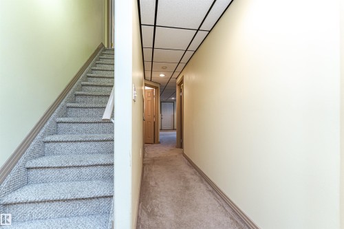 Carpeted staircase with light-colored walls and panel doors - 12241 93 Street Nw, Edmonton, AB - Indoor Photo Showing Other Room