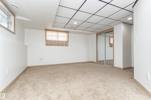 Plush carpet flooring, drop ceiling with recessed lighting, mirrored closet doors, and multiple windows - 12241 93 Street Nw, Edmonton, AB - Indoor Photo Showing Other Room