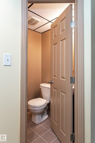 Compact lavatory with square floor tiles and a paneled door - 12241 93 Street Nw, Edmonton, AB - Indoor Photo Showing Bathroom