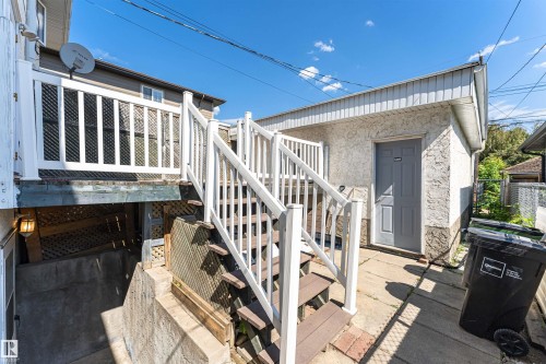 Exterior features include a white-painted wood balustrade, wood-finish stair treads, and a concrete patio - 12241 93 Street Nw, Edmonton, AB - Outdoor With Exterior