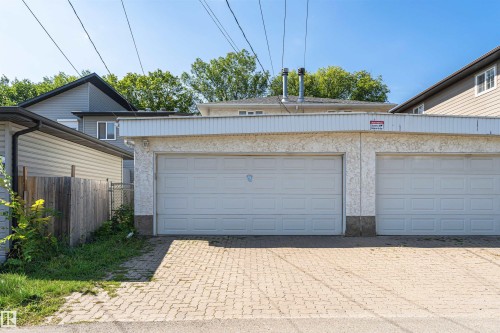 Two-car garage with white panel doors and a textured stucco exterior - 12241 93 Street Nw, Edmonton, AB - Outdoor With Exterior