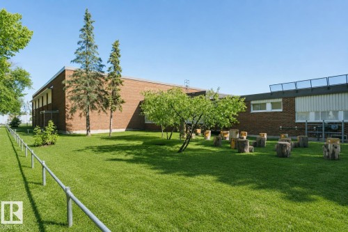 Expansive green space with mature trees, brick exterior, and a metal railing - 12241 93 Street Nw, Edmonton, AB - Outdoor