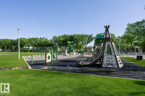 Expansive green space featuring a dedicated playground area with multiple play structures, a slide, and swings - 12241 93 Street Nw, Edmonton, AB - Outdoor