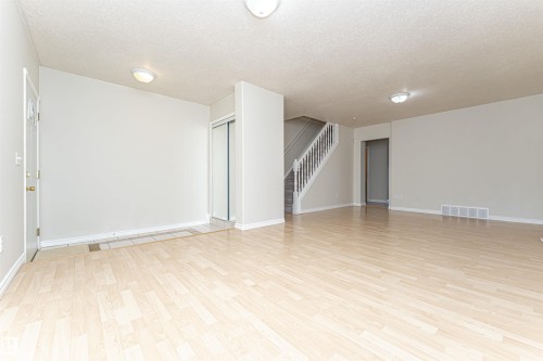Wood-finish flooring, staircase with white risers, flush-mount lighting, and mirrored closet doors - 12241 93 Street Nw, Edmonton, AB - Indoor Photo Showing Other Room