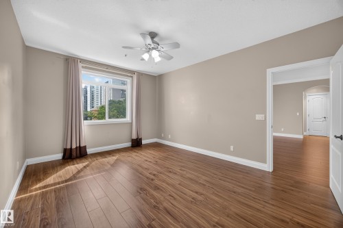 Spacious room featuring wood-finish flooring and neutral wall tones - #401 10178 117 St Nw, Edmonton, AB - Indoor Photo Showing Other Room