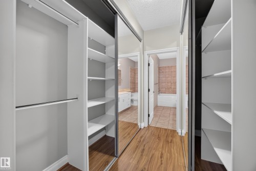 Closet featuring mirrored sliding doors, integrated shelving, and hanging rods - #401 10178 117 St Nw, Edmonton, AB - Indoor Photo Showing Other Room