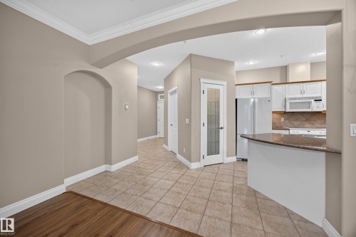 Kitchen featuring white cabinetry, built-in microwave, and a breakfast bar with stone-finish countertop - #401 10178 117 St Nw, Edmonton, AB - Indoor Photo Showing Kitchen