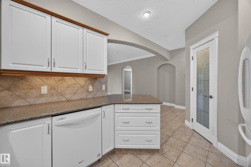 Kitchen featuring white cabinetry, a tiled backsplash, and granite countertops - #401 10178 117 St Nw, Edmonton, AB - Indoor Photo Showing Kitchen