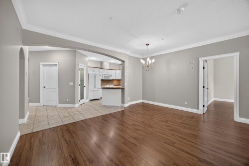 Open concept living space featuring wood-finish flooring, light gray walls, and white crown molding - #401 10178 117 St Nw, Edmonton, AB - Indoor Photo Showing Other Room