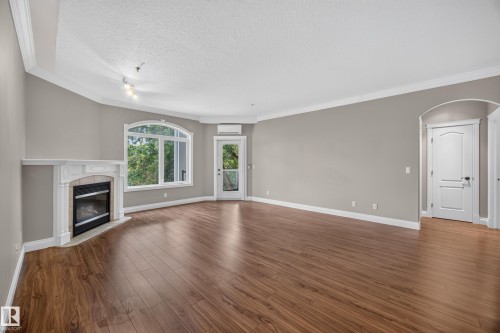Open living area featuring wood-finish flooring and neutral wall tones - #401 10178 117 St Nw, Edmonton, AB - Indoor Photo Showing Living Room With Fireplace