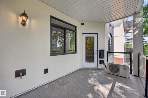 Private exterior patio featuring a textured floor and a glass safety railing - #401 10178 117 St Nw, Edmonton, AB - Outdoor With Exterior