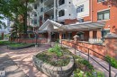 Brick facade building featuring a covered entryway, decorative iron fencing, a sloped access ramp, and planted garden beds - #401 10178 117 St Nw, Edmonton, AB  - Outdoor With Deck Patio Veranda 