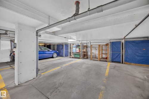 Underground parking garage featuring concrete flooring, exposed overhead piping, and fluorescent lighting - #401 10178 117 St Nw, Edmonton, AB - Indoor Photo Showing Garage