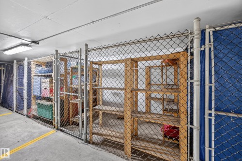 Individual storage units with chain-link fencing, concrete flooring, and overhead fluorescent lighting - #401 10178 117 St Nw, Edmonton, AB - Indoor With Storage
