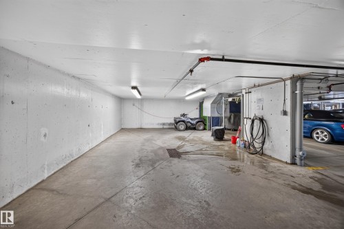Concrete flooring with exposed concrete walls, fluorescent lighting, and visible overhead piping - #401 10178 117 St Nw, Edmonton, AB - Indoor Photo Showing Garage