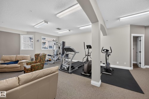 Dedicated fitness area featuring exercise equipment, carpeted flooring, and neutral wall tones - #401 10178 117 St Nw, Edmonton, AB - Indoor Photo Showing Gym Room