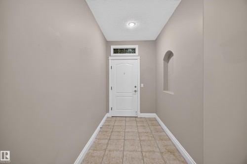 Entryway featuring a white paneled door with an arched transom window, recessed lighting, neutral wall tones, ceramic tile flooring, and an arched wall niche - #401 10178 117 St Nw, Edmonton, AB - Indoor Photo Showing Other Room