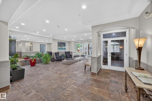 Spacious lobby featuring natural stone tile flooring, recessed lighting, crown molding, and a decorative water feature - #401 10178 117 St Nw, Edmonton, AB - Indoor Photo Showing Other Room
