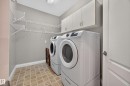 Dedicated laundry area featuring a front-load washer and dryer, upper cabinetry, extensive wire shelving, and tiled flooring - #401 10178 117 St Nw, Edmonton, AB  - Indoor Photo Showing Laundry Room 