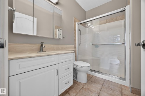 Bathroom featuring a walk-in shower with glass enclosure, white vanity with integrated sink, light-toned countertop, and medicine cabinet storage - #401 10178 117 St Nw, Edmonton, AB - Indoor Photo Showing Bathroom