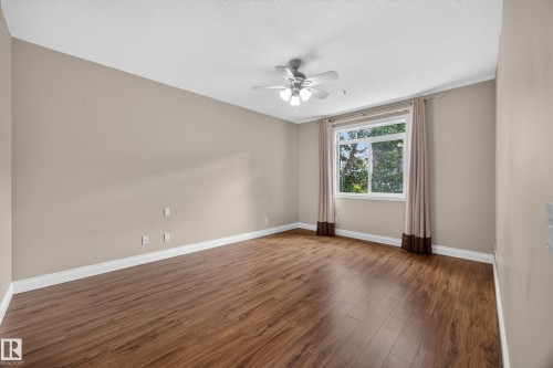 Spacious room featuring wood-finish flooring, neutral-toned walls, and a multi-pane window - #401 10178 117 St Nw, Edmonton, AB - Indoor Photo Showing Other Room