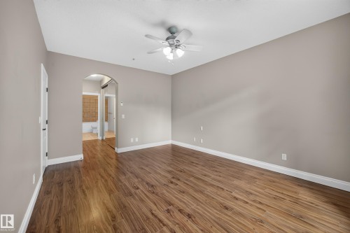 Spacious interior room featuring wood-finish flooring and neutral wall tones - #401 10178 117 St Nw, Edmonton, AB - Indoor Photo Showing Other Room