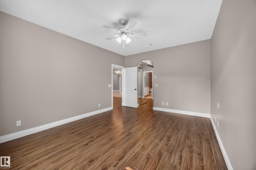 Spacious room featuring wood-finish flooring, light taupe walls, and white trim - #401 10178 117 St Nw, Edmonton, AB - Indoor Photo Showing Other Room