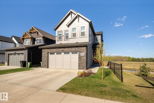 Two-story exterior with light gray siding and stone accents - 7135 Edgemont Way Nw, Edmonton, AB 
