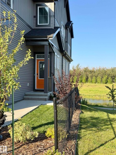 Modern exterior with gray siding, black trim, and a vibrant orange entry door - 7135 Edgemont Way Nw, Edmonton, AB 