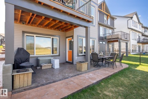 Covered patio with a concrete surface, featuring an orange entry door, and a built-in outdoor fire pit - 7135 Edgemont Way Nw, Edmonton, AB 